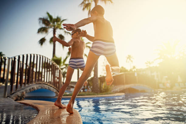 istock Two boys jumping into the resort pool 1152204455