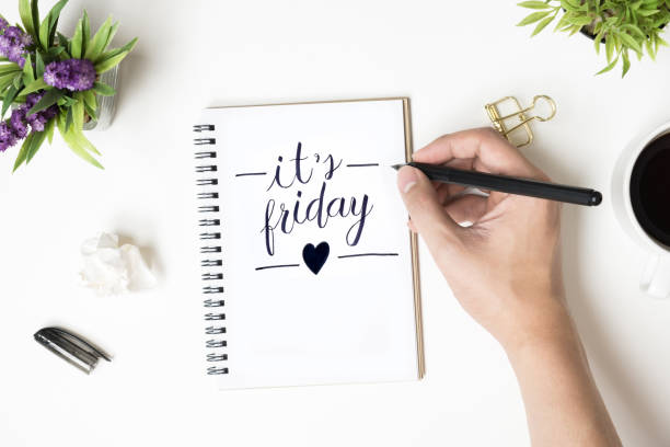istock Man is writing it's Friday calligraphy text on the notebook on white office desk table. Top view, flat lay. 1152204641