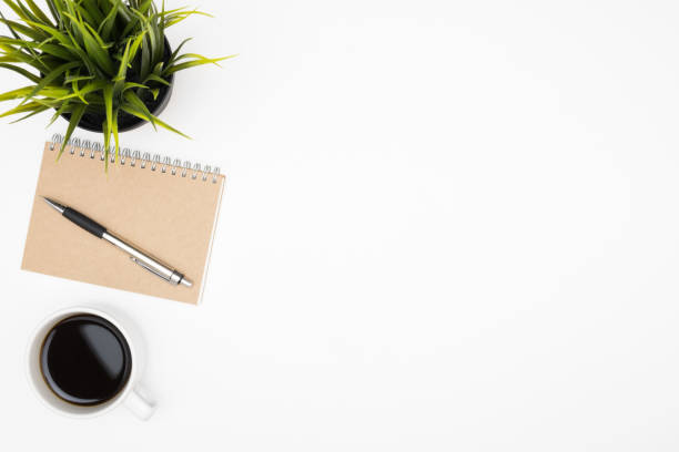 istock White office desk table with cup of coffee and notebook with pen. Top view with copy space, flat lay. 1152205220