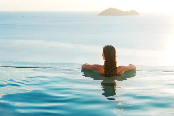 девушка в бассейне на закате с видом на горы и море - poolside enjoyment sensuality blue стоковые фото и изображения