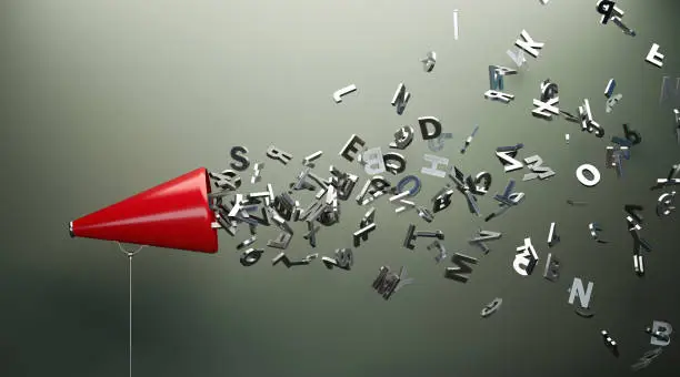 Red megaphone and silver colored alphabet letters in front of gray wall. Horizontal composition with copy space. Great use for announcement concepts.