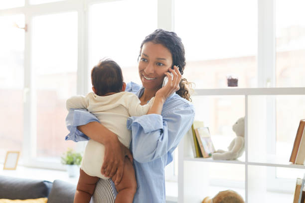istock Young mother talking on phone while holding baby 1152209628