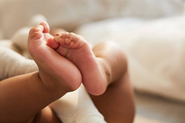 Cute baby feet Close-up of unrecognizable cute baby shaking feet while lying in bed, innocence concept child care photos stock pictures, royalty-free photos & images