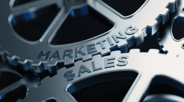 Metal cogs are turning. Marketing and sales words are written on the cogs. Horizontal composition with copy space.