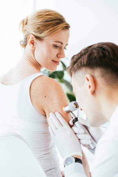 istock dermatologist in latex gloves holding dermatoscope while examining beautiful patient with skin disease 1152216286
