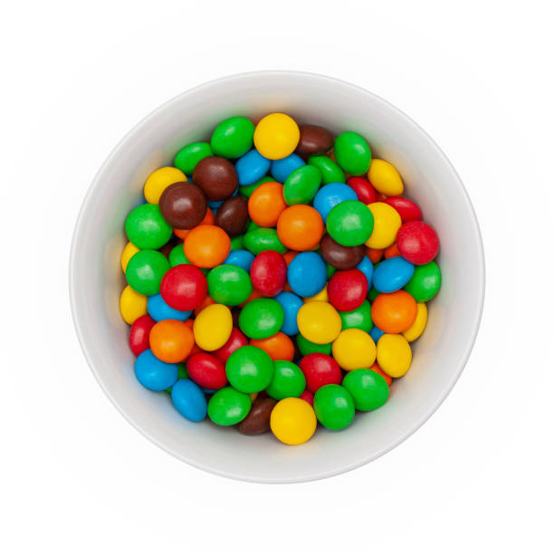 istock White bowl with chocolate round colored candies on a white background. Isolated. Top view. 1152217868