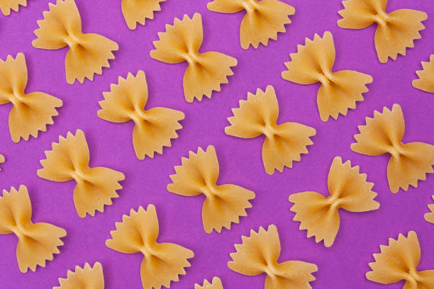 istock Raw pasta farfalle on purple background. Poster. 1152218923