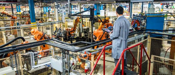 ingénieur surveillant le processus de production automatisé dans une usine - bras robotisé outil de production photos et images de collection