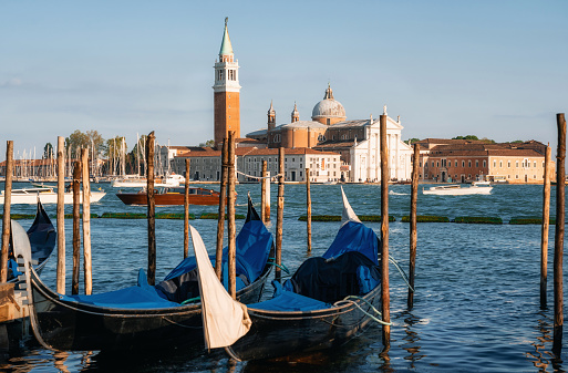Row of gondolas moored beside the Riva degli Schiavoni against boats and San Giorgio Maggiore island, Venice, Italy