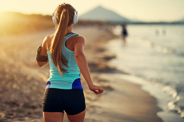 jogging d’adolescent de fille sur la plage - shorts rear view summer beach photos et images de collection