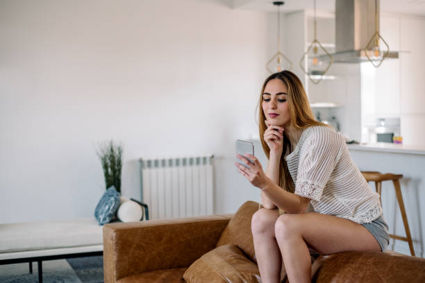 istock Happy woman with smartphone on couch 1152230605