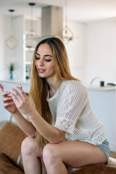 istock Happy woman with smartphone on couch 1152230608
