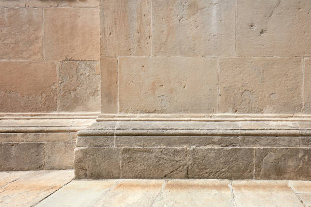 Ancient stone wall with molding and corner, floor background in sunlight