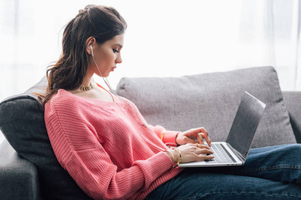 istock indian woman with earphones using laptop with blank screen while lying on sofa 1152233679