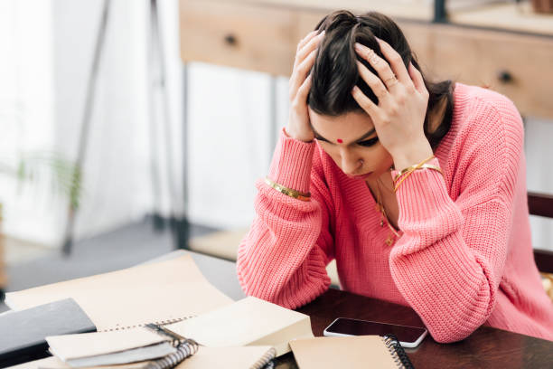 istock tired indian student with headache looking at notebooks at home 1152233757