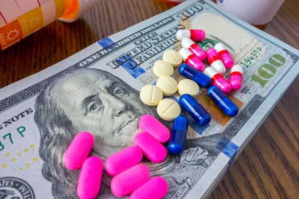 Medical expenses Medicine pills on a pile of 100 dollar bills and social security card social security social security card identity us currency stock pictures, royalty-free photos & images