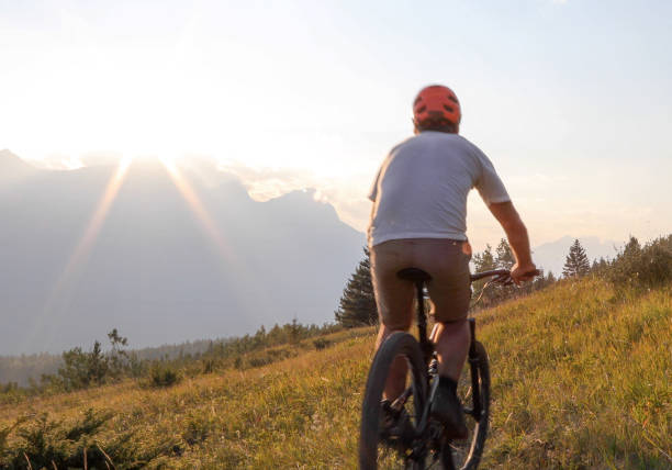 istock Mountain biker rides along trail in meadow at sunrise 1152236939