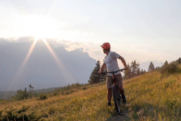istock Mountain biker rides along trail in meadow at sunrise 1152236969