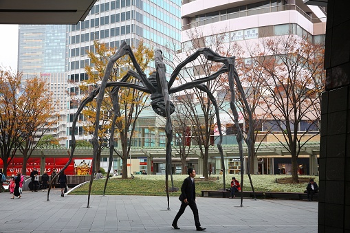 People walk by Roppongi Hills spider monument in Tokyo, Japan. The Spider is a popular meeting place for local people. Maman sculpture created by Louise Bourgeois in 1999.