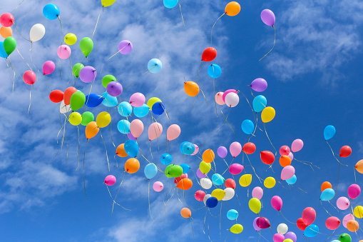 Five multicolored balloons floating in the blue sky over the green hill with copy space.