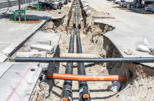 istock District heating pipeline reparation and reconstruction site parallel with the street with construction site safety net fence and insulated pipes for hot water in the trench before winter season come 1152239930