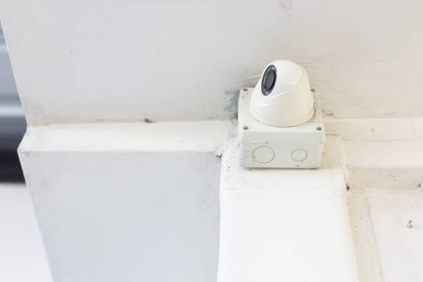 istock closeup of closed circuit television camera or CCTV and box control on white concrete ceiling. 1152240569