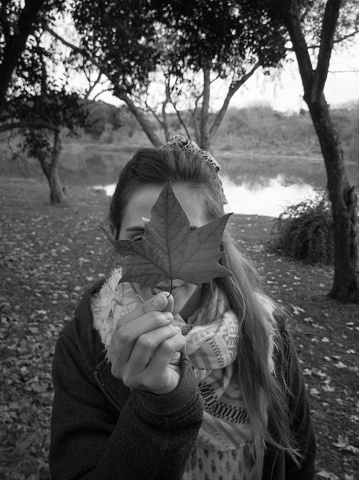 a black and white portrait of a girl behind a Maple Leaf in the autumn of Canada