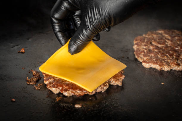 putting cheese in the hamburger on griddle griddle stock pictures, royalty-free photos & images