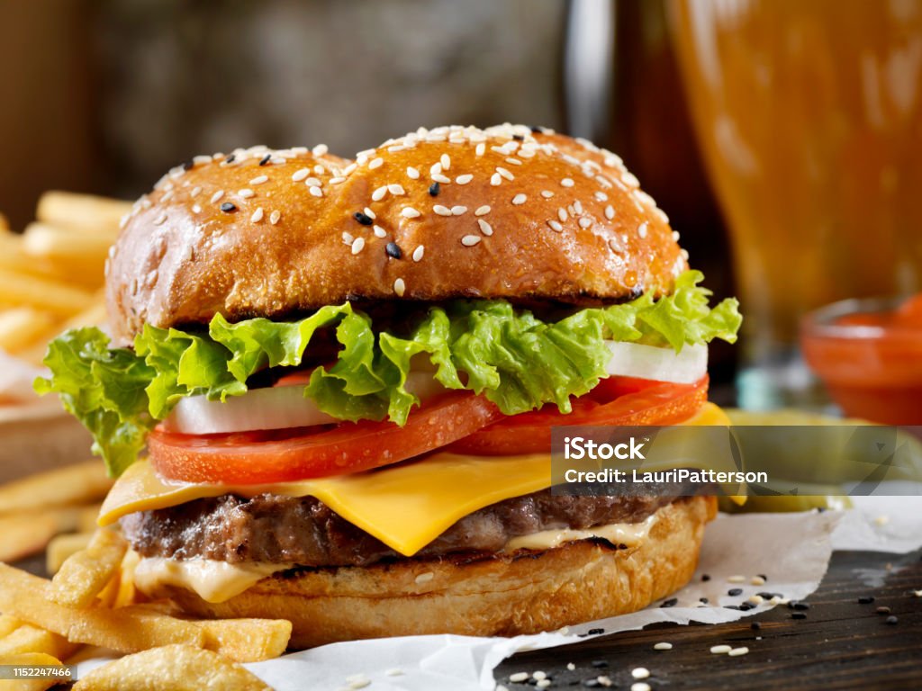 Cheeseburger clássico em um bolo do brioche com fritadas e um milkshake - Foto de stock de Hamburguer royalty-free