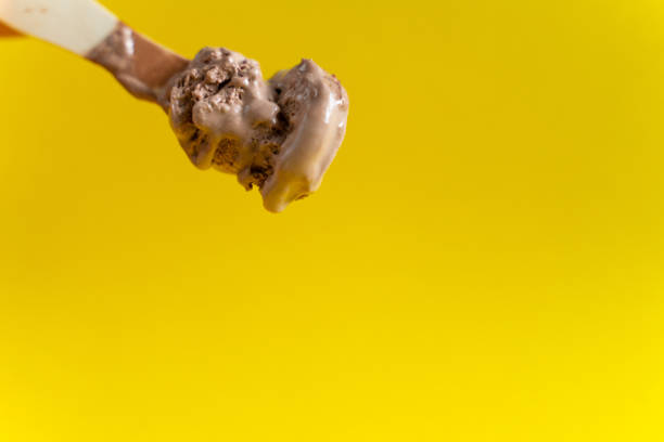 istock chocolate ice cream on wooden spoon on yellow background 1152248894