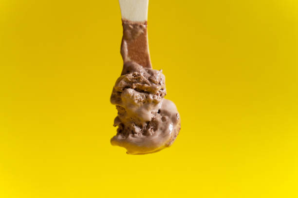 istock chocolate ice cream on wooden spoon on yellow background 1152248900