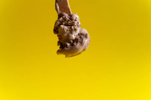 istock chocolate ice cream on wooden spoon on yellow background 1152248909