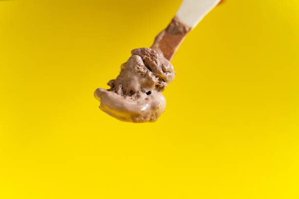 istock chocolate ice cream on wooden spoon on yellow background 1152248911