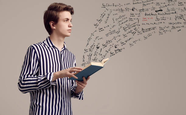 istock Young handsome man in striped shirt reading a book on gray background 1152249135
