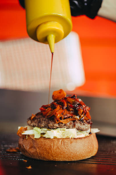 istock Cook preparing burger adding the sauce on the cream cheese. Three burgers. 1152253514