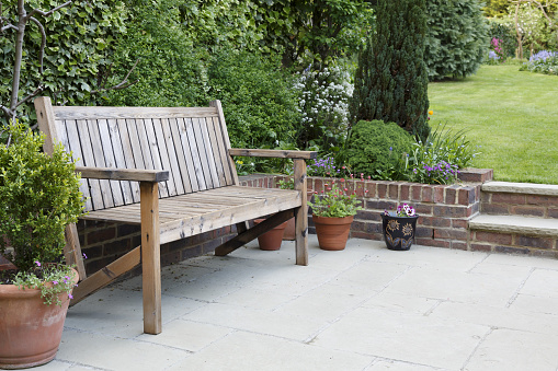British back garden with a paved patio and traditional wooden bench