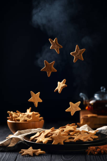 Falling stars shaped cookies with powdered sugar. Vertical composition on a dark background stock photo