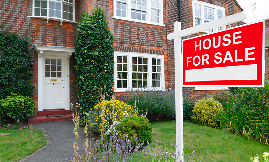 For sale sign outside a house in an affluent suburb of London