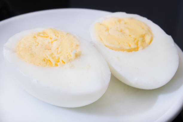 istock one boiled egg cut in half on a white plate and black background 1152260668