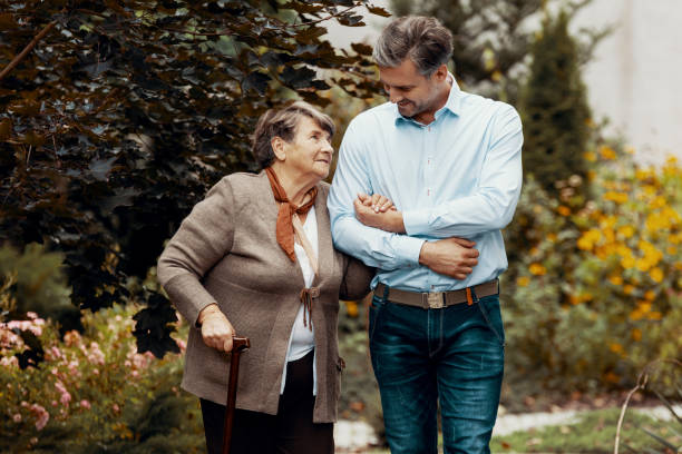 istock Man supporting weak senior woman with walking stick in the garden 1152263025
