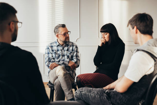 School counselor talking to depressed teenager during group therapy School counselor talking to depressed teenager during group therapy emo hair guys stock pictures, royalty-free photos & images