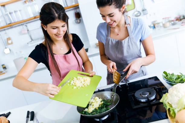 istock Two beautiful young women adding potatoes to the chards into the pan. 1152268303