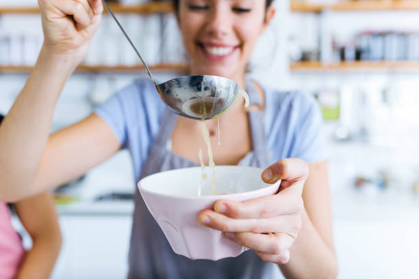 jovencita sirviendo sopa de verduras en la cocina. - utensilio para servir fotografías e imágenes de stock