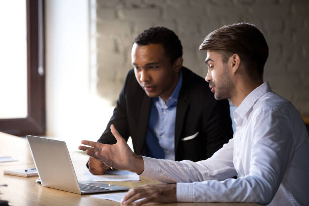 istock African intern receiving instructions from caucasian colleague sitting using laptop 1152268812