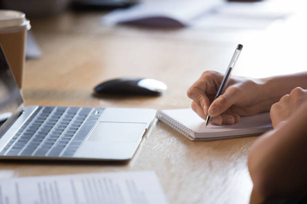 cerrar las manos femeninas sosteniendo la pluma escribiendo en el bloc de notas - self examination fotografías e imágenes de stock