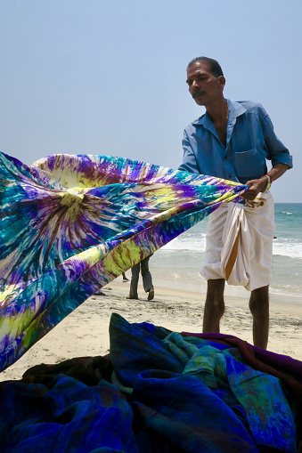 Stock photo of head scarves and souvenirs being sold on the beach by a local Indian man.