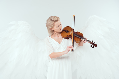 beautiful woman in angel costume with wings playing violin isolated on white