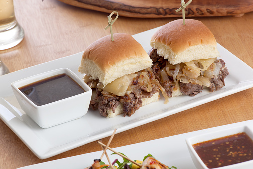 two beef sliders with au jus sauce