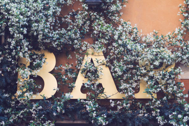 front view close up of cafe bar street signage exterior facade covered in green leaves and white flowers
