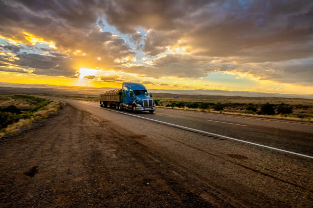 long haul semi truck rast down a four lane highway in a beautiful sunset - four lane highway stock-fotos und bilder
